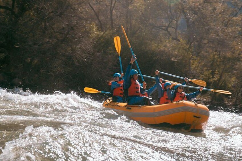 Un groupe de personnes à bord d’un radeau jaune navigue sur une rivière bordée d’arbres. 1