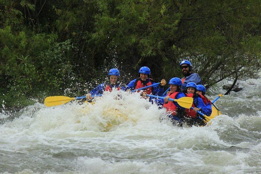 Un groupe de personnes à bord d’un radeau jaune navigue sur une rivière bordée d’une végétation luxuriante. 3