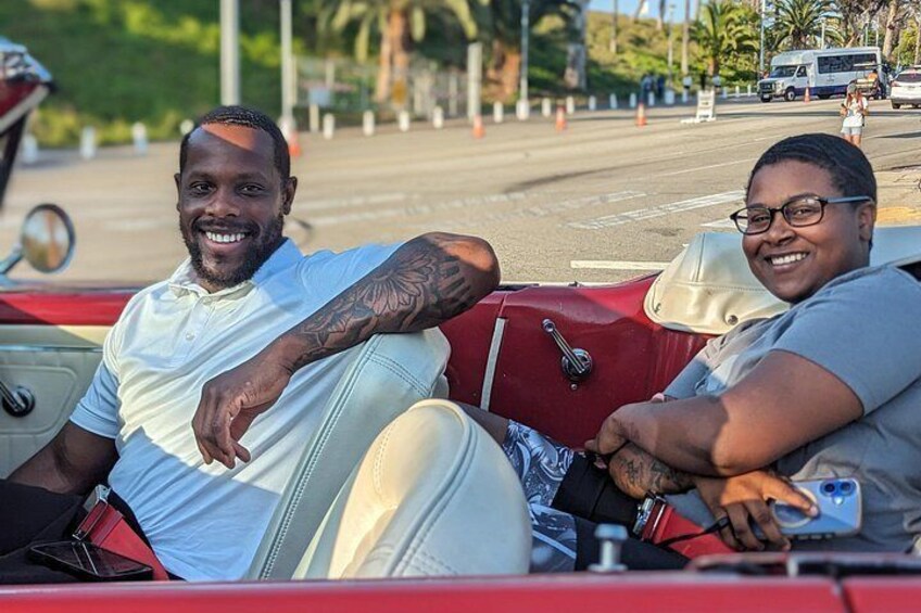Two people in a convertible car. 4