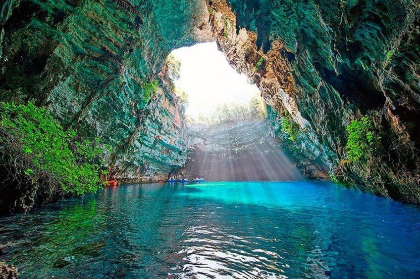 Una grotta naturale con un corpo idrico al suo interno, circondata da pareti rocciose e vegetazione. 5