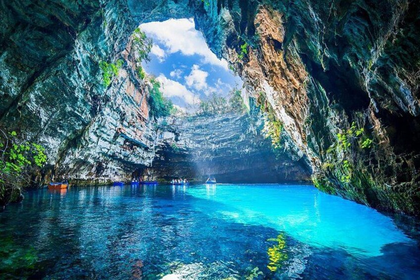 Una grotta con acqua blu cristallina, pareti rocciose e una barca in lontananza. 1