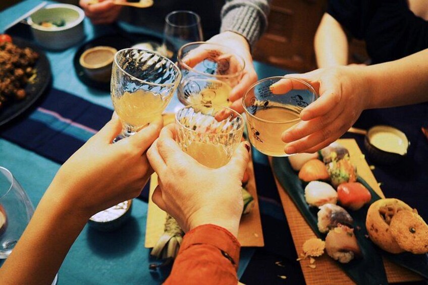 Des personnes qui trinquent avec des boissons, une assiette de biscuits et une nappe bleue. 2