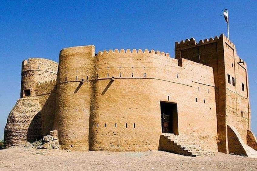 A large, historic stone castle with a round tower and a flag on top. 3
