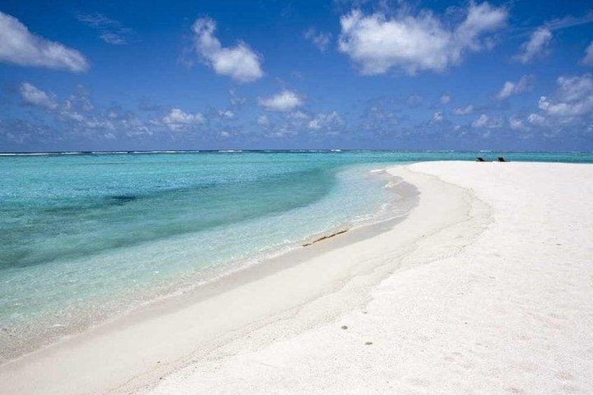A white sandy beach with clear turquoise water and a clear blue sky. 5