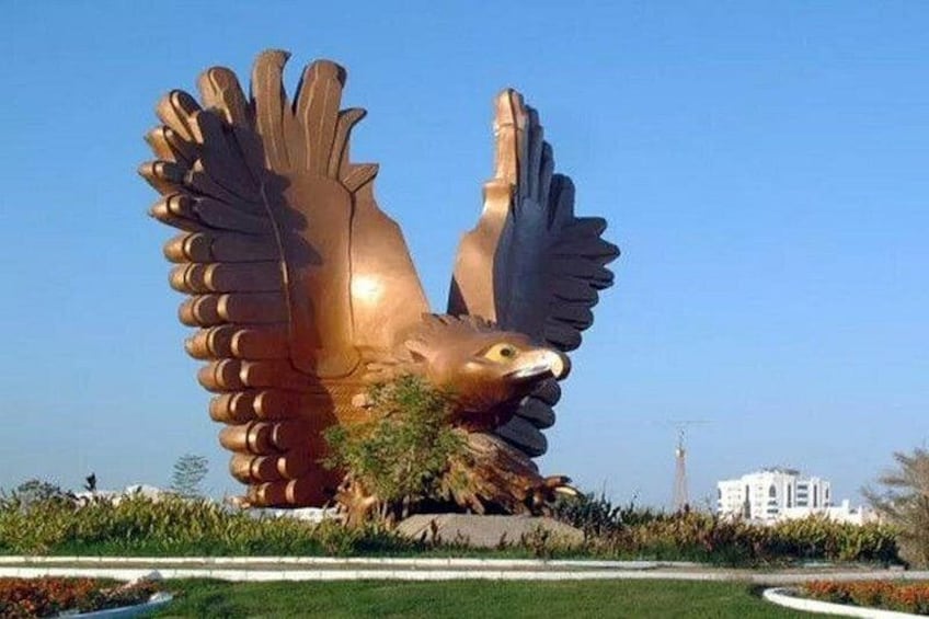 A large bronze eagle sculpture with outstretched wings in a landscaped area with grass and trees. 2