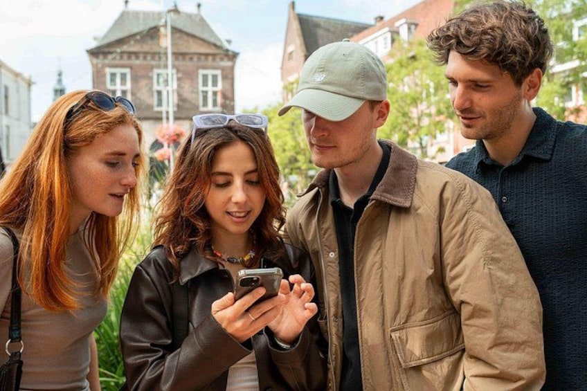 Four people standing outdoors, one holding a smartphone. 5