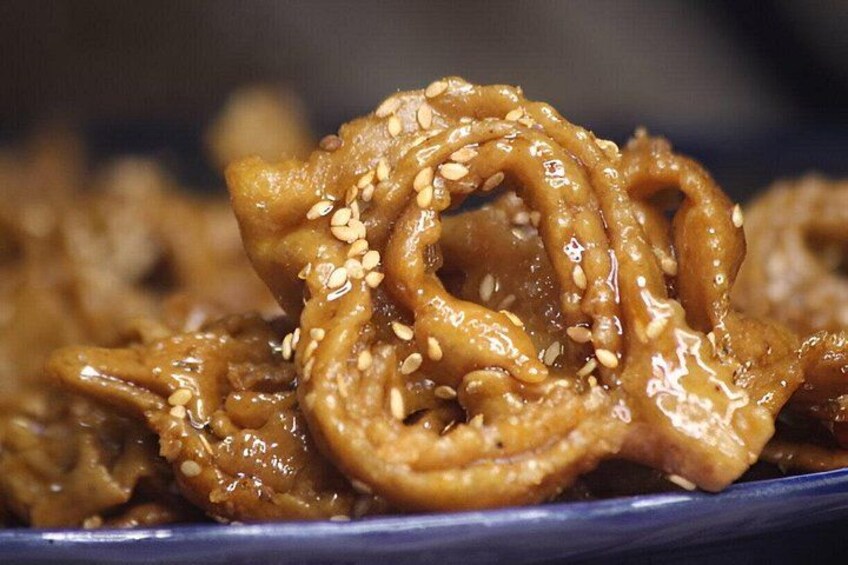 A close-up of a dish with a glossy, caramelized coating and sesame seeds. 4