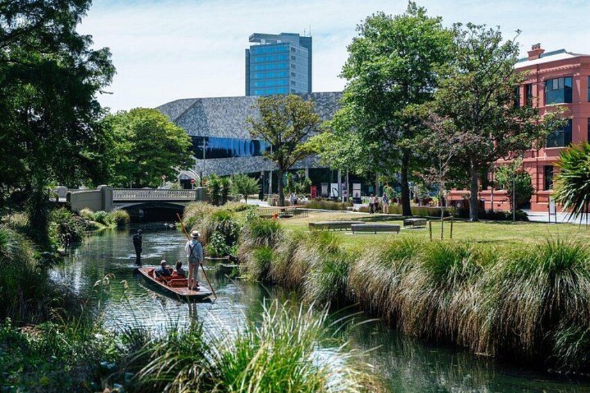 Un río con un puente, un edificio rojo y una estructura moderna de vidrio al fondo. 1