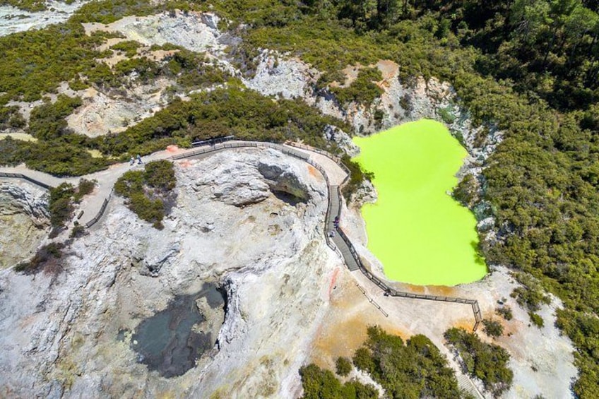 A rocky landscape with a bright green pond surrounded by trees and a winding path. 5
