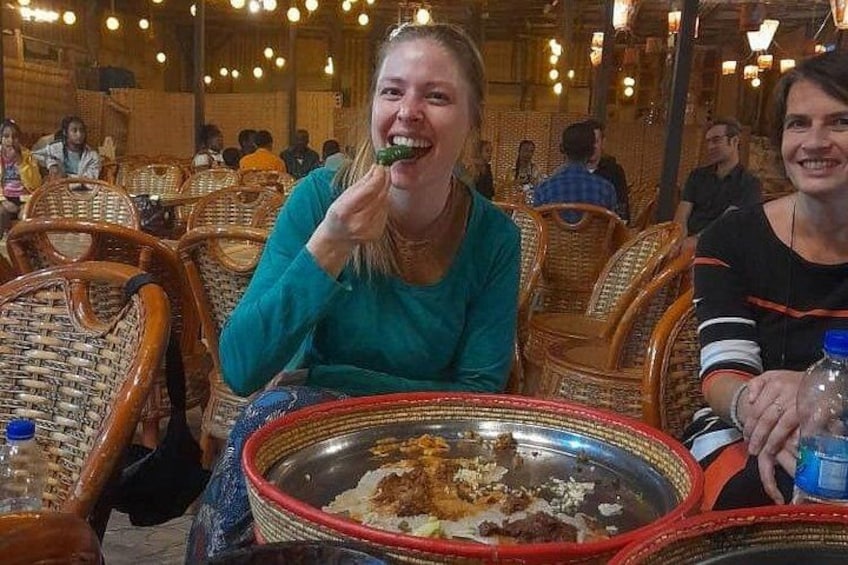 A person sitting at a table with a metal tray containing food. 1