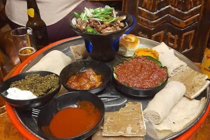 A traditional Ethiopian meal with injera, various stews, and a bottle of beer. 3