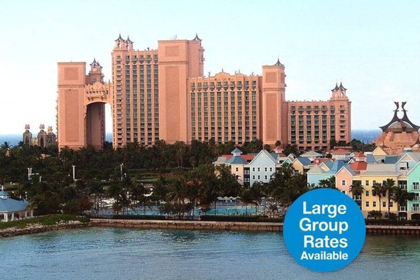 A large hotel complex with a prominent archway, a body of water in the foreground, and smaller buildings in the background. 1