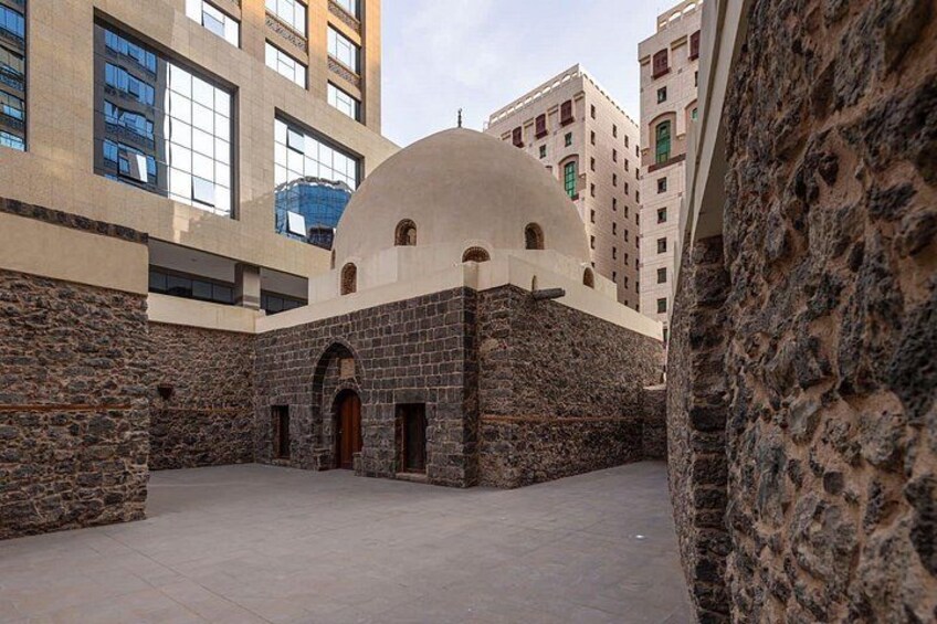 A courtyard with a stone building featuring a dome and arched entrance. 2