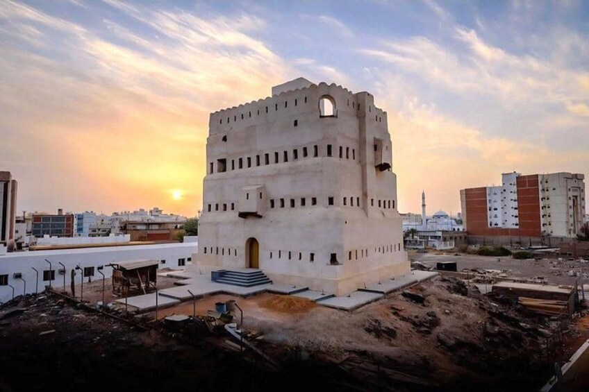A historical tower with a square base and a central archway, surrounded by construction debris and modern buildings. 4