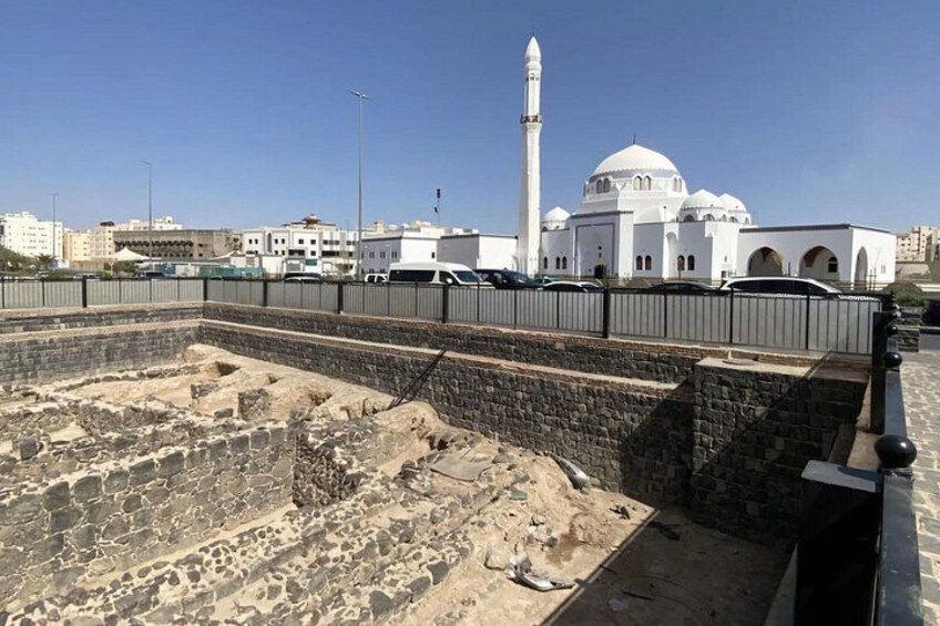 A mosque with a minaret, a white dome, and a stone wall with a moat. 5