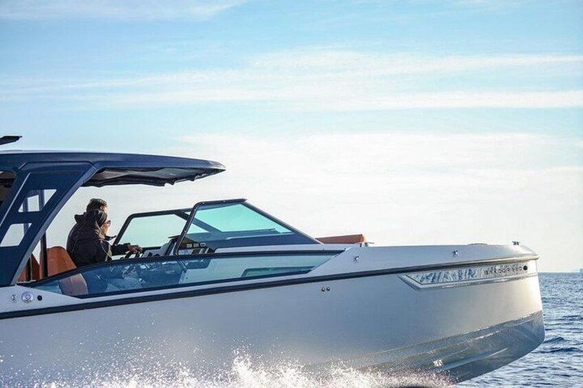 A speedboat with a person driving, water spray behind it, and a clear sky. 2