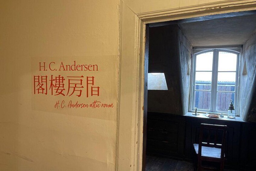 Een kamer met een raam, een bureau en een stoel. Op de muur staat tekst in een vreemde taal. 2