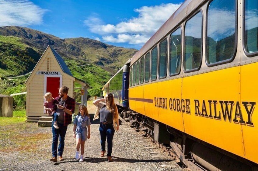 A yellow train labeled 'TAIRI GI Gorge Railway' with a family walking beside it. 1