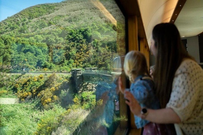 A woman and a child looking out a window at a bridge over a valley. 2