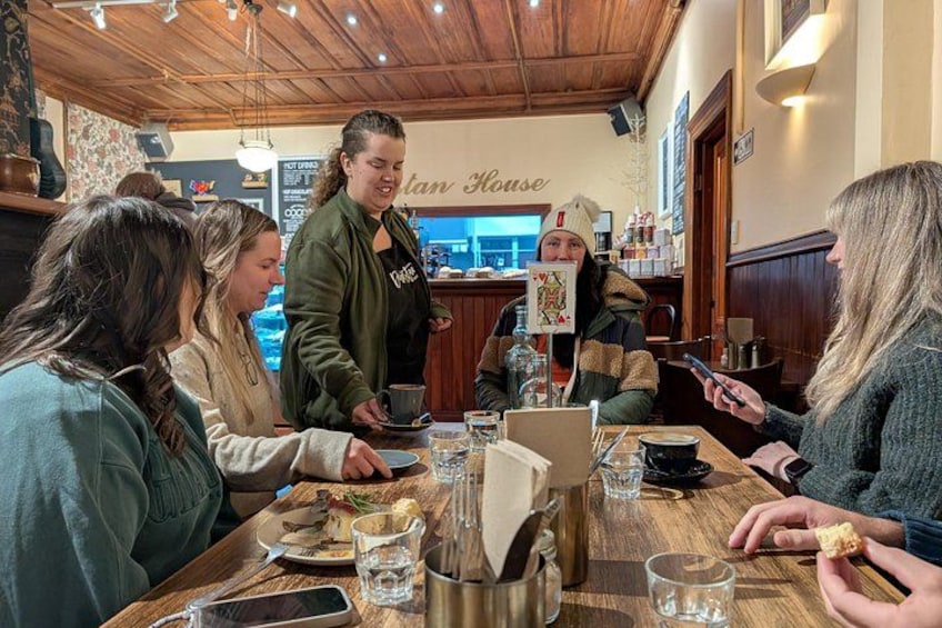 A group of people dining at a restaurant with wooden interiors and a menu board in the background. 3