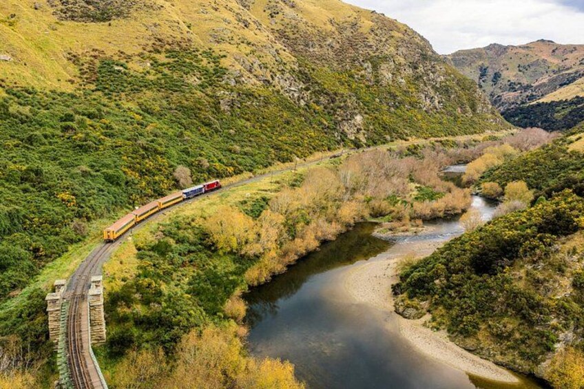 A train traveling along a track through a valley with a river and hills. 2