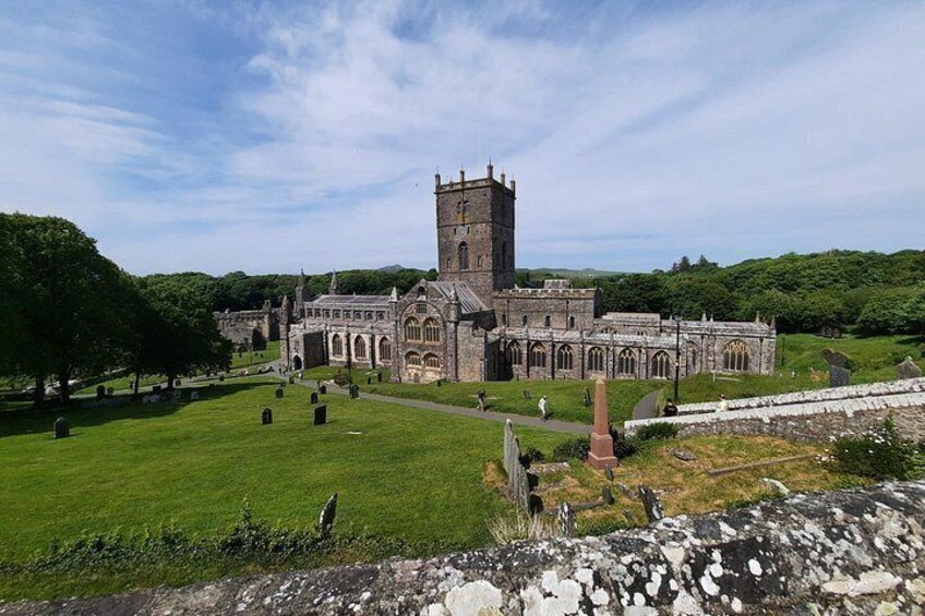 A historic church with a prominent tower, surrounded by a well-maintained cemetery and lush green landscape. 4