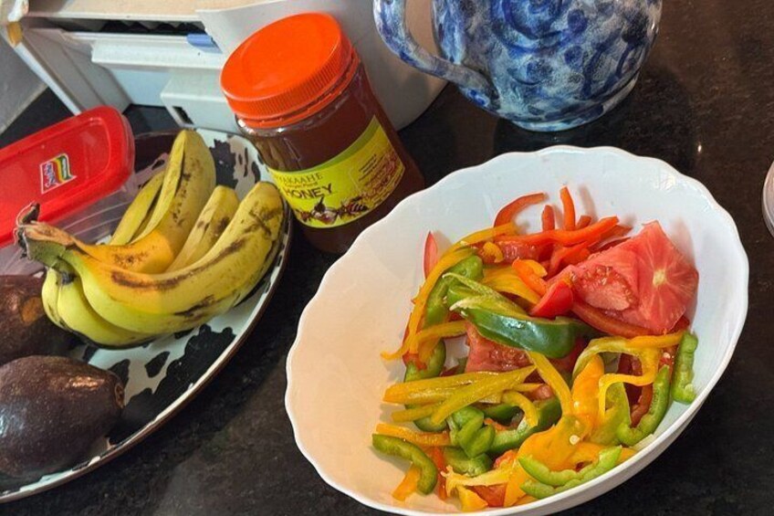 A kitchen counter with a plate of sliced vegetables, a bowl of bananas, and a jar of honey. 3