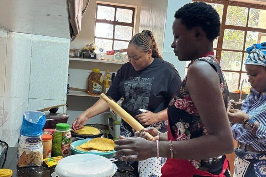 A kitchen with people preparing food, a rolling pin, bowls, and various food items. 2