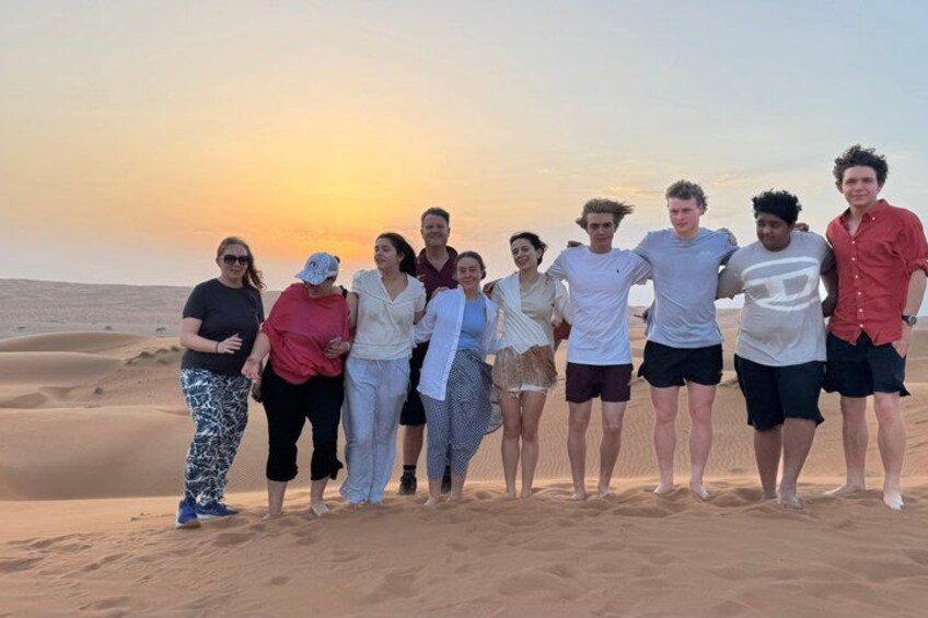 Un gruppo di persone in piedi su una spiaggia sabbiosa, con un tramonto sullo sfondo. 4