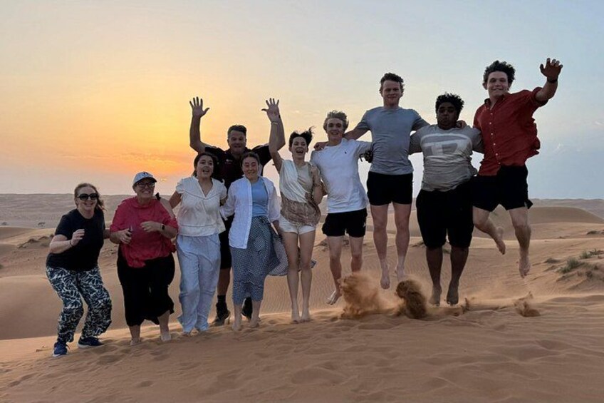 Un gruppo di persone salta sulla sabbia al tramonto. 2