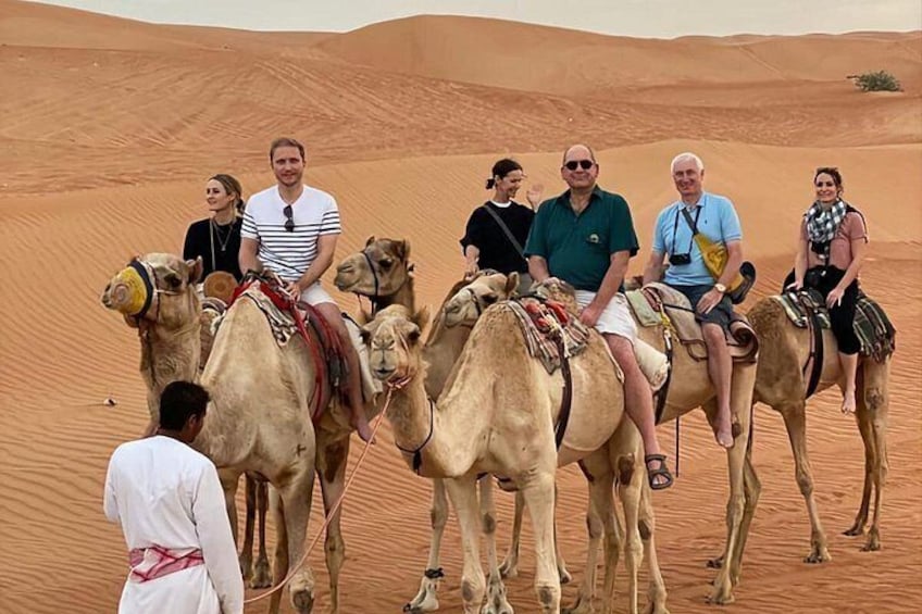 Un gruppo di persone cavalca cammelli in un paesaggio desertico. 1
