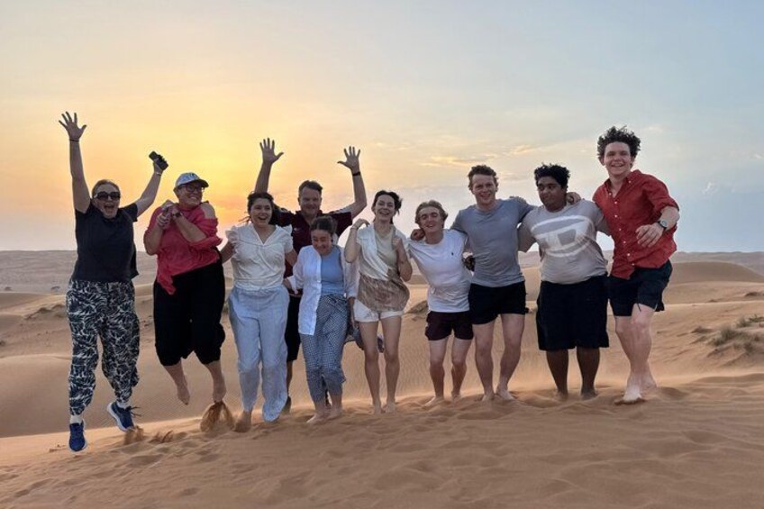 Un gruppo di persone in piedi su una spiaggia sabbiosa, con un tramonto sullo sfondo. 5