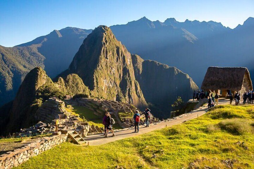 Rovine di Machu Picchu con turisti, un sentiero in pietra e montagne sullo sfondo. 4
