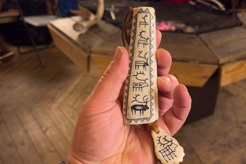 A hand holding a carved wooden object with inscriptions and symbols. 2