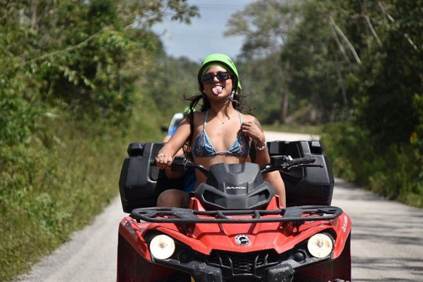 A person riding a red ATV on a paved road surrounded by greenery. 2