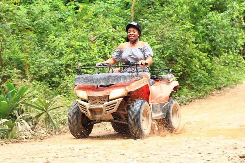 A person riding an ATV on a dirt path surrounded by dense greenery. 4