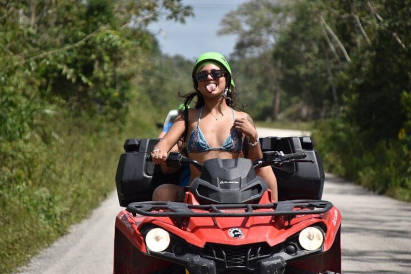 Une personne conduit un quad rouge sur une route asphaltée, entourée de verdure. 2