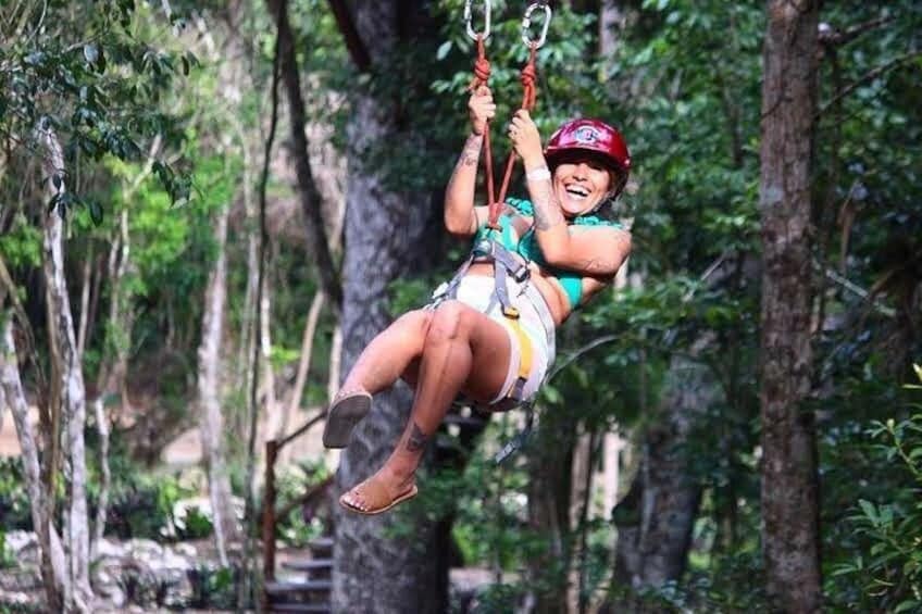 En person som åker på en zipline som är upphängd i en skog. 2