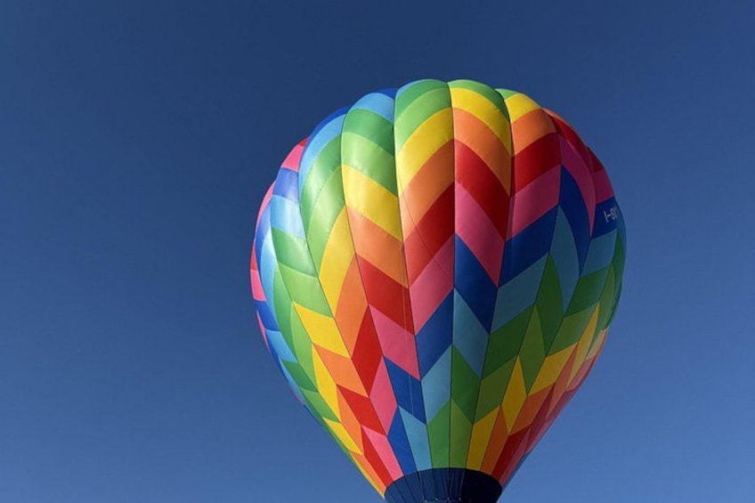 A hot air balloon with a multicolored pattern against a clear blue sky. 4