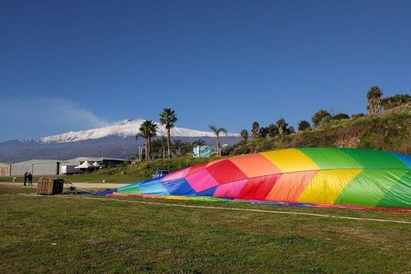 A colorful, rainbow-striped canopy in a grassy field with a mountain in the background. 3