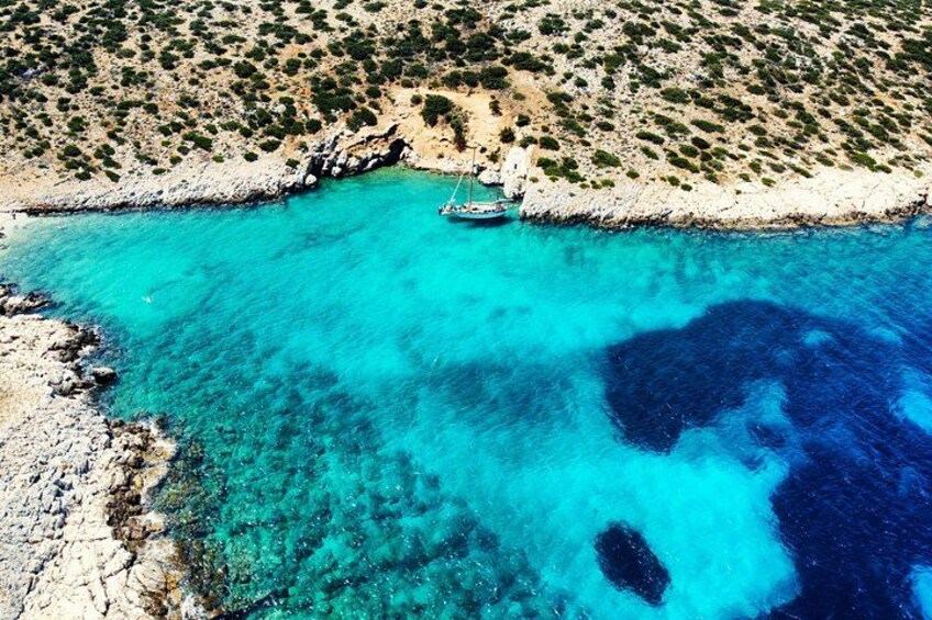 A turquoise sea with a rocky coastline and a boat anchored near the shore. 4