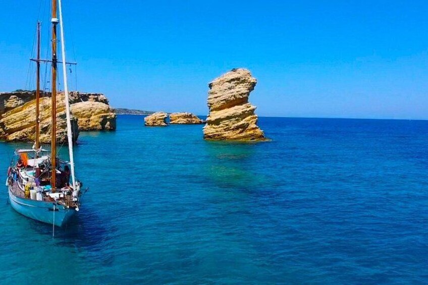 A sailboat near rocky formations in clear blue waters. 3