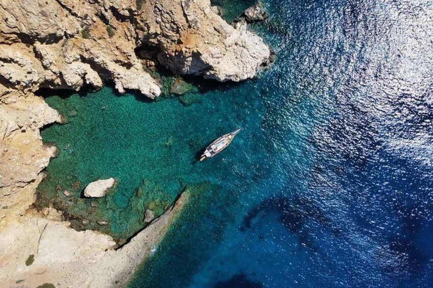A rocky coastline with clear blue waters and a boat. 2