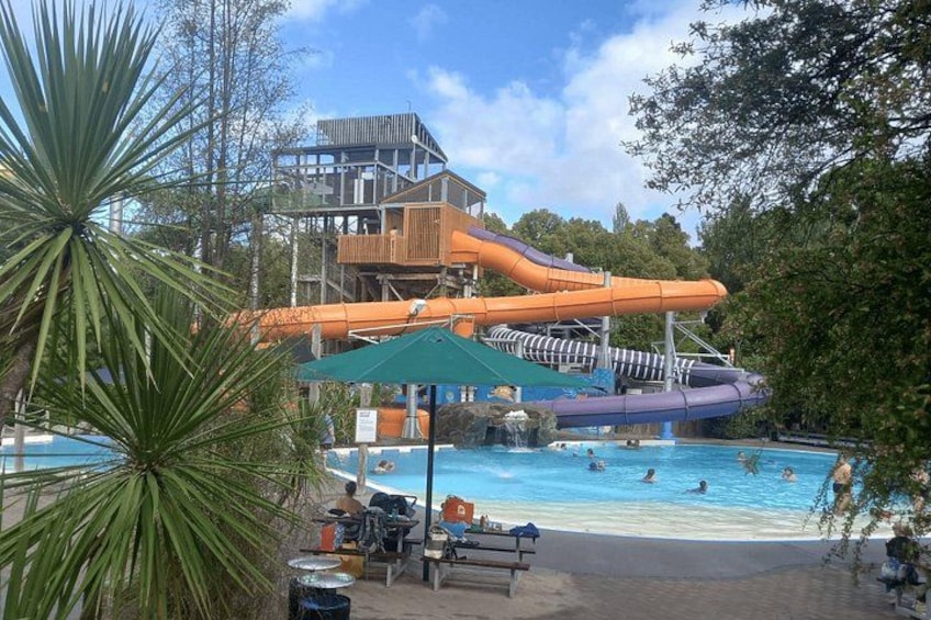 A water park with a large pool, a water slide, and a wooden deck. 3