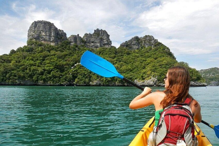 A person kayaking on a calm body of water with a mountainous landscape in the background. 3