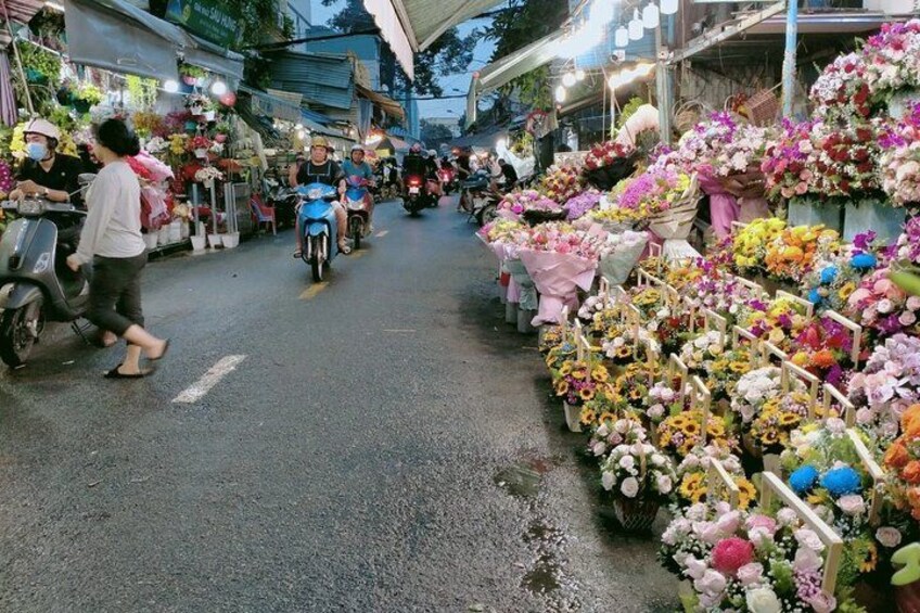 A street market with flower stalls and motorbikes. 3