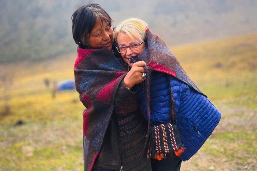 Two people embracing in a natural landscape with a grassy field and distant mountains. 2