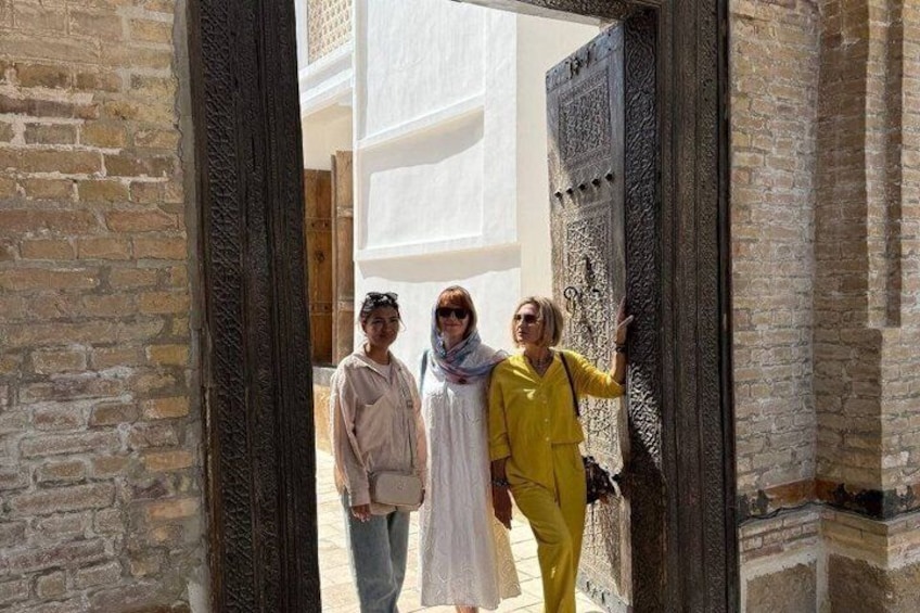 A group of people standing in an open doorway with a brick wall and a wooden door. 4