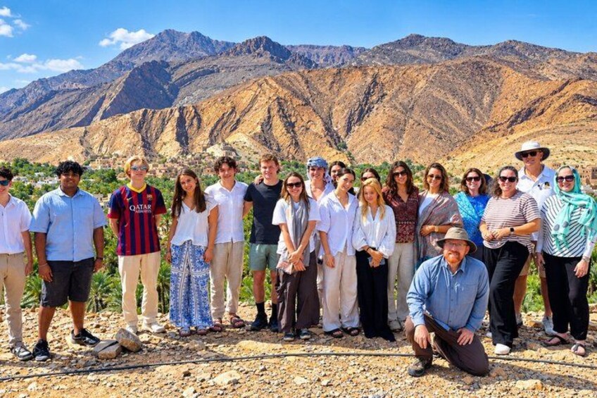 Un grupo de personas de pie en un terreno rocoso al aire libre, con montañas al fondo. 1