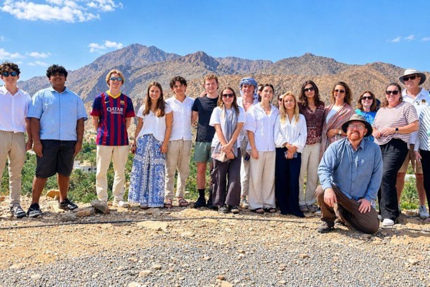 A group of people standing in a desert landscape with mountains in the background. 1